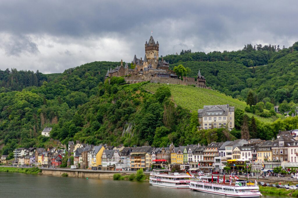 Beautiful landscape of Cochem Castle in Germany with lush greenery and townscape.